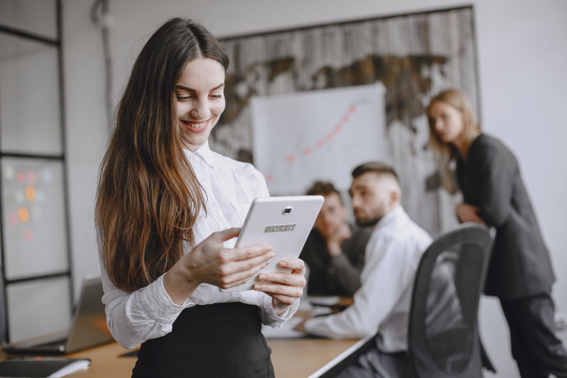 Une responsable consulte une tablette, son équipe derrière elle